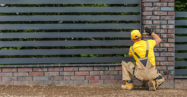 Handwerker bei der Gartenzaunpflege